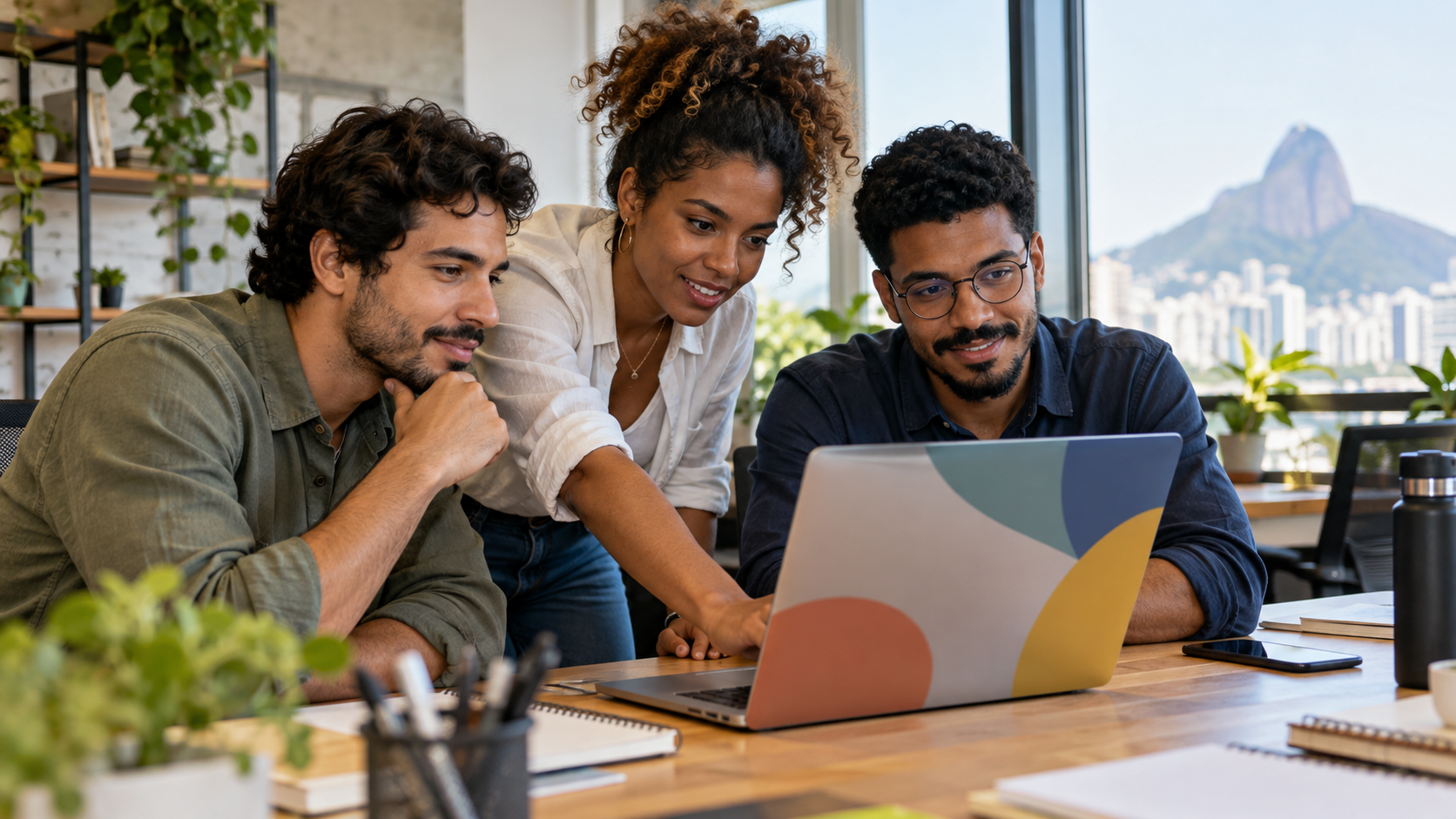 Equipe de três pessoas numa mesa de escritório com um notebook, conversando sobre como organizar o atendimento da empresa pelo WhatsApp.